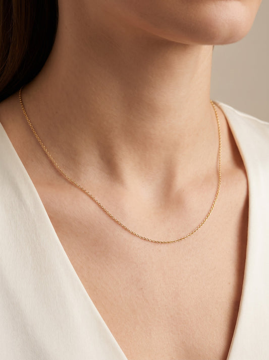 HELIOR 1.1mm 18K yellow gold cable chain necklace, worn at the neckline.