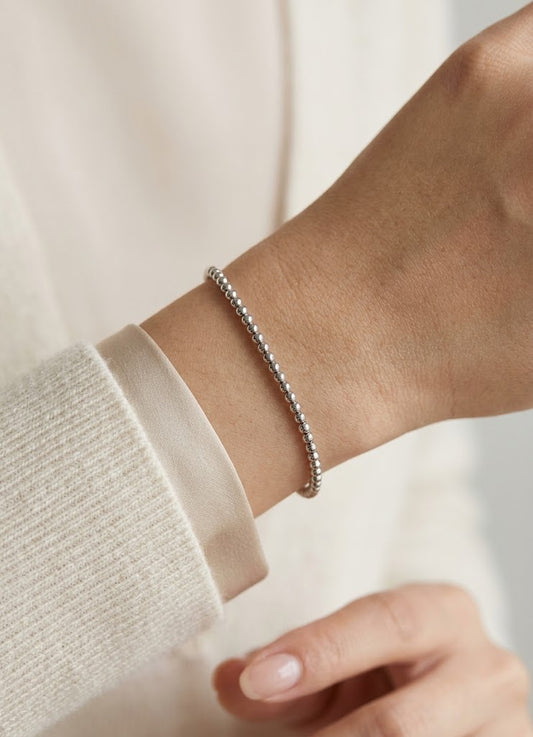 HELIOR Orbit PT950 platinum bead bracelet worn on a wrist with an ivory sleeve; fit varies with wrist size and chosen length