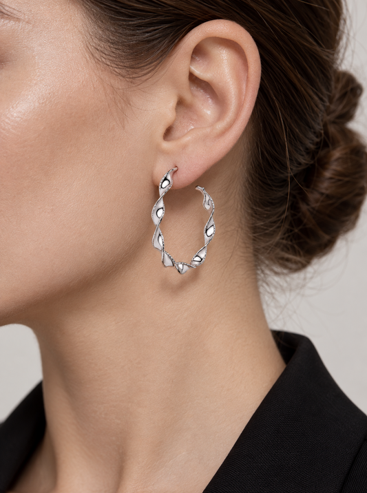 Platinum ribbon twist hoop earring worn close up with a black jacket