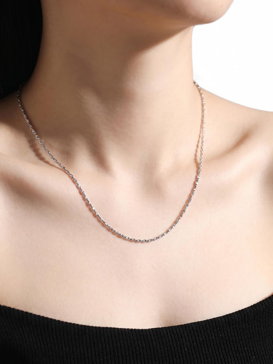Woman wearing laser-cut platinum olive bead chain with black neckline