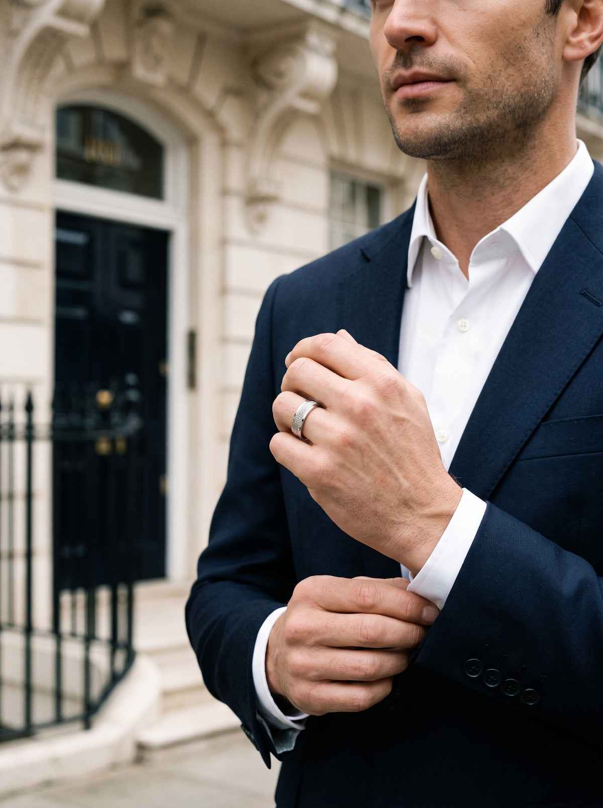 Man in a navy suit wearing the HELIOR Clous platinum ring while adjusting his cuff.
