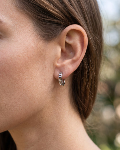 Side view of a PT950 platinum heart cut-out huggie earring worn on the earlobe.
