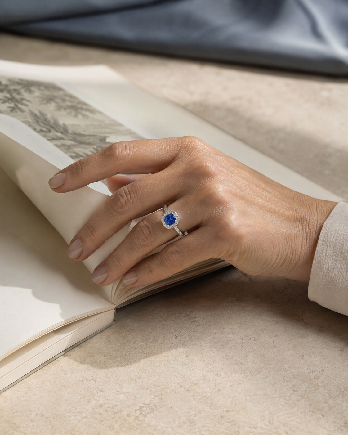 Woman wearing a PT950 platinum sapphire halo ring while turning a book page