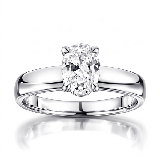 An oval-cut diamond solitaire engagement ring in a polished four-prong setting on a sleek platinum band, shown against a clean white background with a soft reflection below.