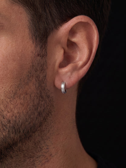 Vela textured platinum huggie hoop worn close to a man's earlobe