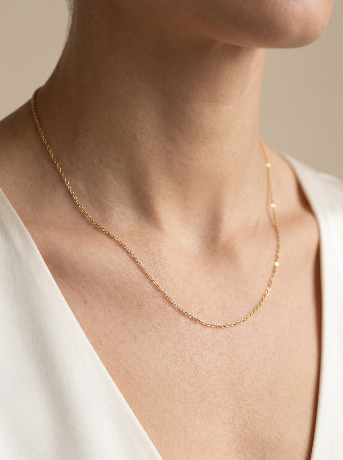HELIOR 1.3mm 18K yellow gold cable chain necklace, worn at the neckline.