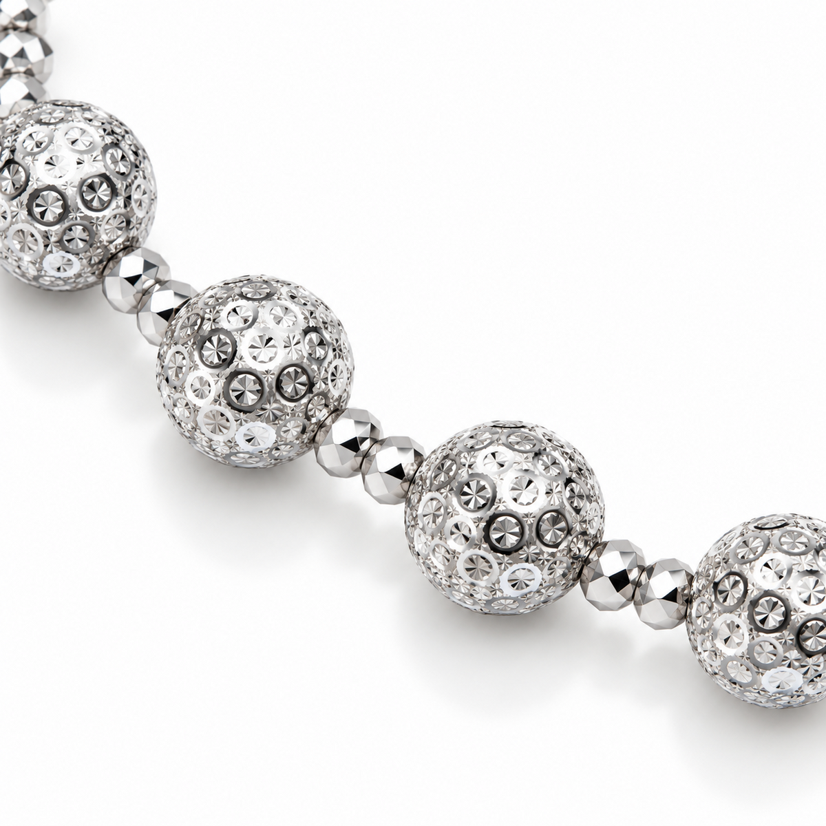 Macro detail of HELIOR Aster PT950 platinum bracelet with patterned 8mm round beads separated by pairs of smaller faceted beads.