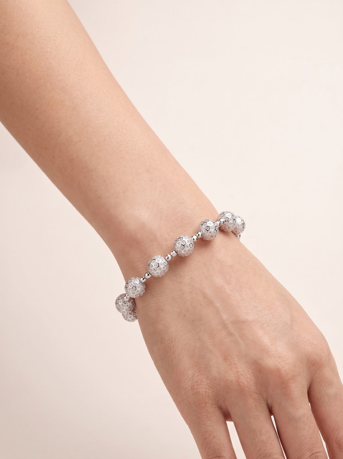 Aster 8mm PT950 platinum bead bracelet by HELIOR worn on a woman's wrist against a soft neutral background.