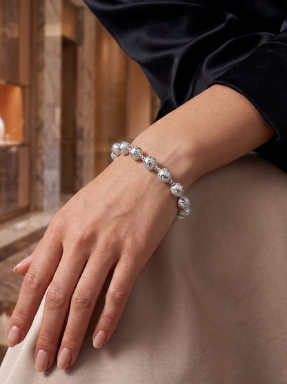HELIOR Aster platinum bracelet worn with dark clothing, showing the reflective patterned beads and paired smaller spacers.