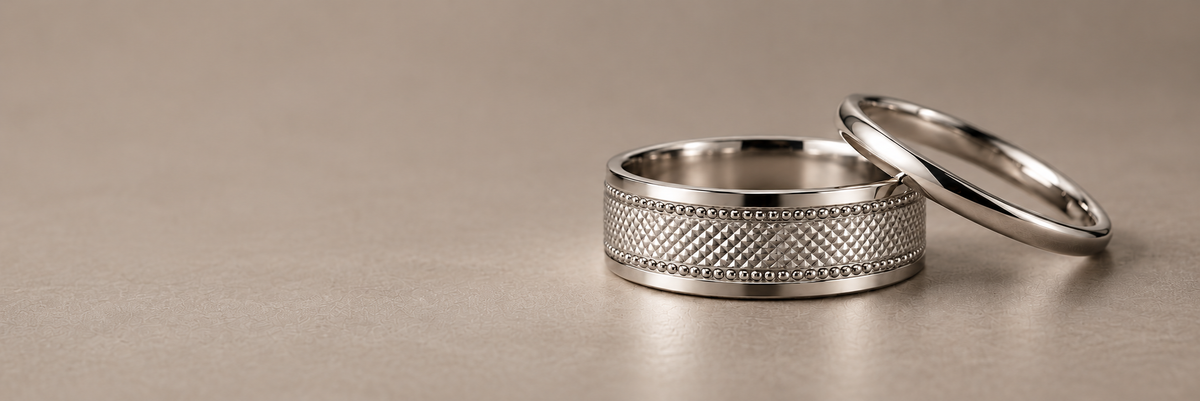 HELIOR Clous platinum band with faceted centre and twin milgrain borders beside a polished platinum band on a warm grey background.