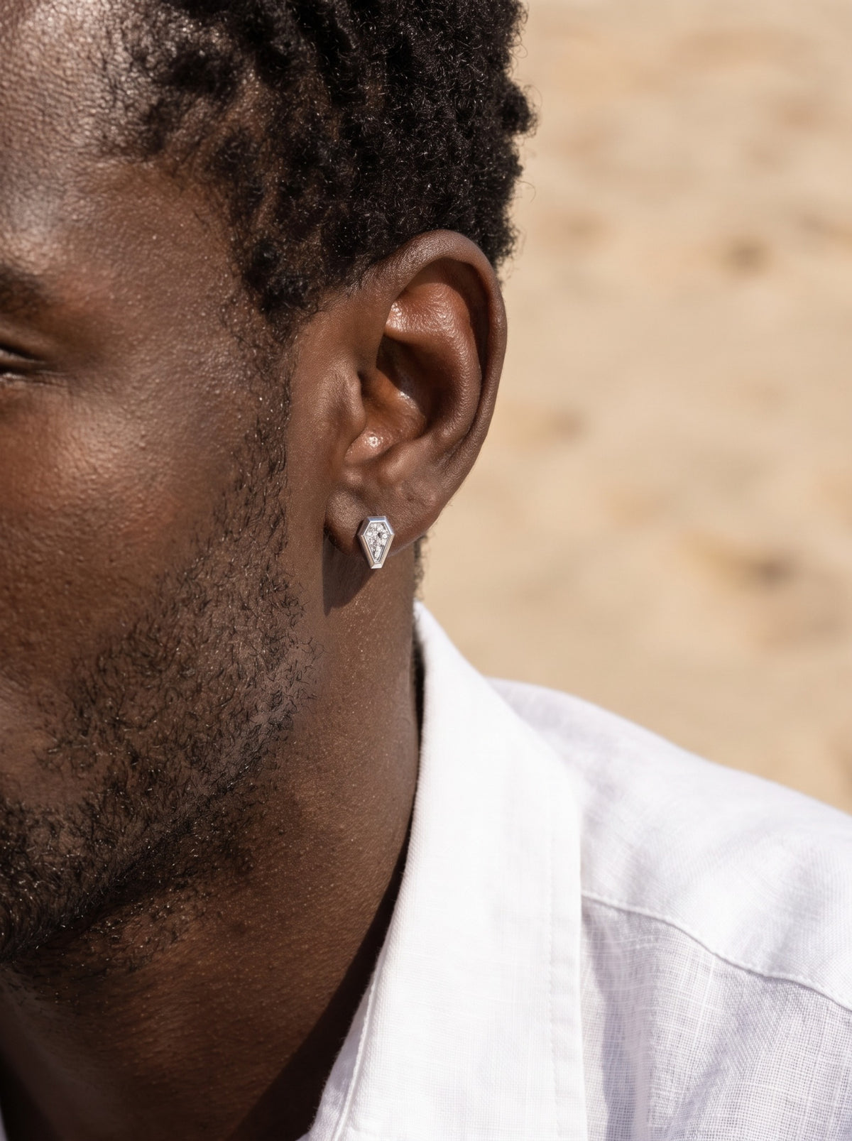 HELIOR Crest PT950 platinum shield stud earring worn in natural sunlight with a white shirt