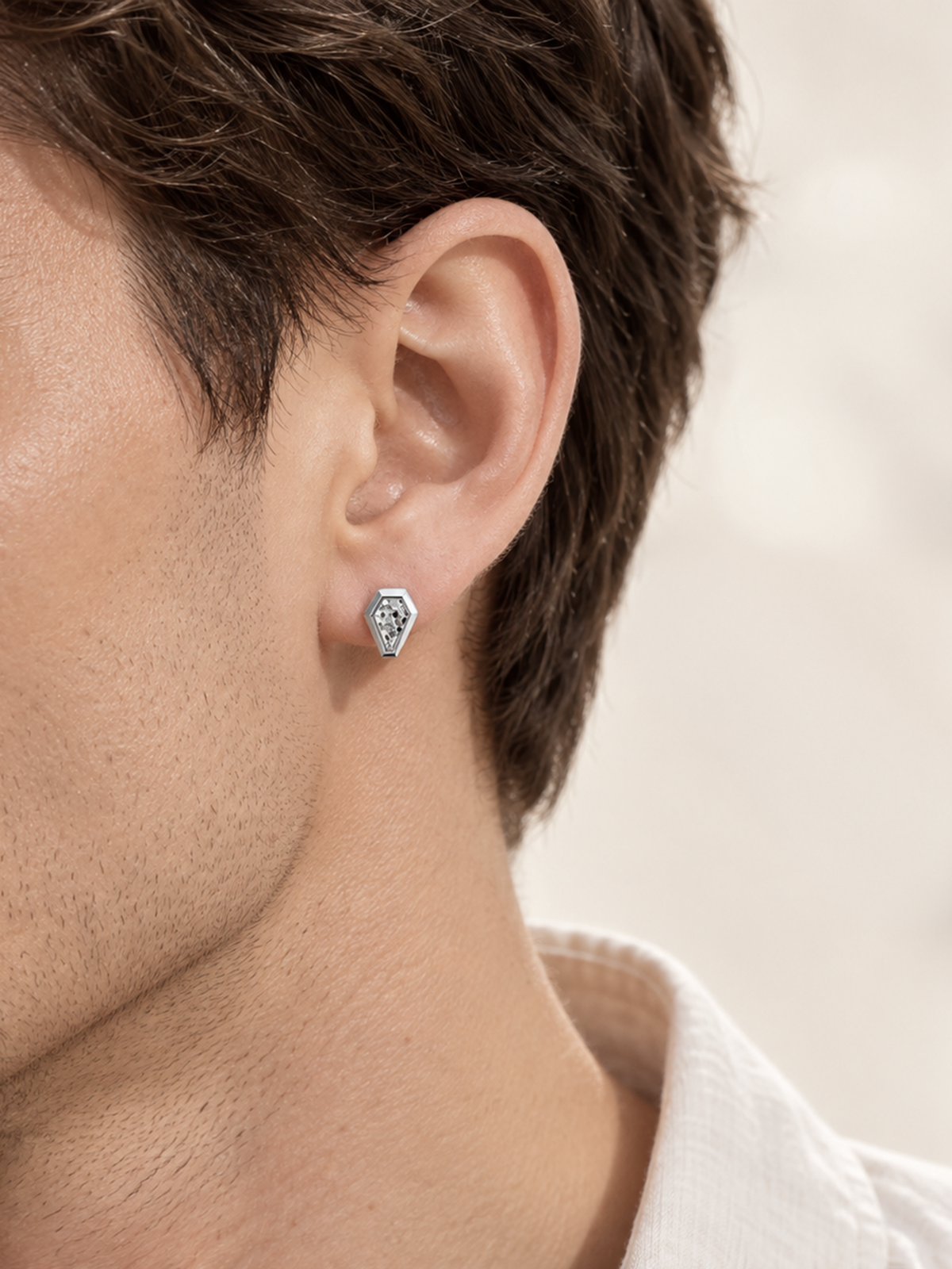 HELIOR Crest platinum shield stud earring worn on the ear with a light outfit
