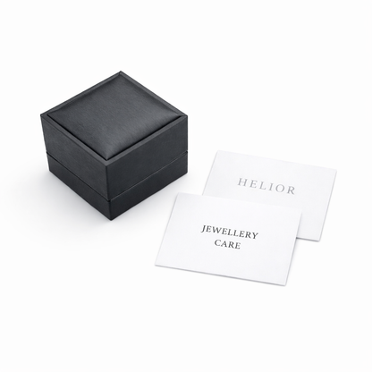 HELIOR jewellery packaging with a dark presentation box, HELIOR card and jewellery care card on a light background.