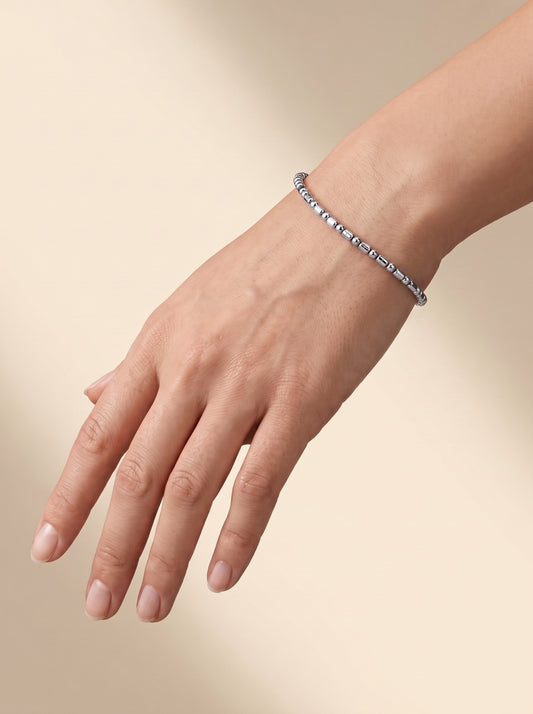 HELIOR Orbit 2.4mm platinum faceted bead bracelet worn on a wrist against a warm neutral background, showing its delicate proportions.