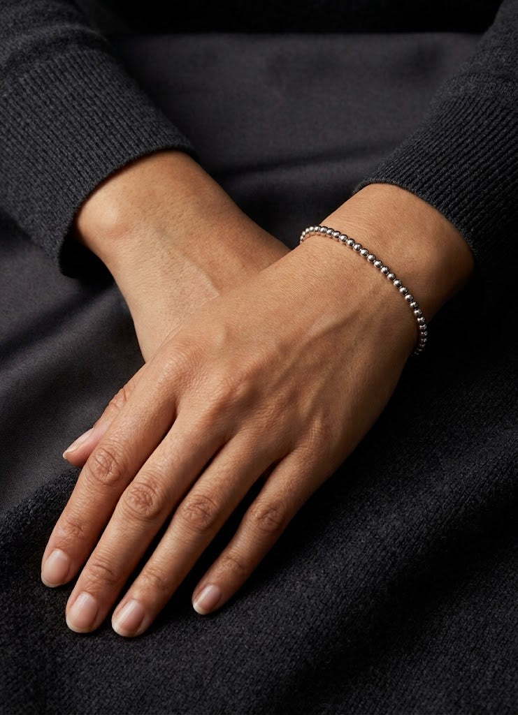 HELIOR Orbit PT950 platinum bead bracelet worn with a dark knit outfit, showing the polished round beads