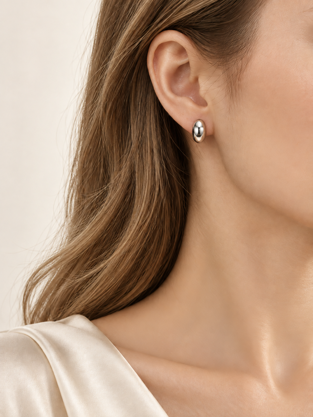 HELIOR PT950 platinum moon stud earring worn with an ivory blouse, showing its polished oval front