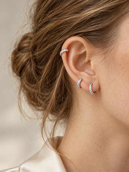 Three Spiral white gold lab-grown diamond huggie earrings styled on the ear