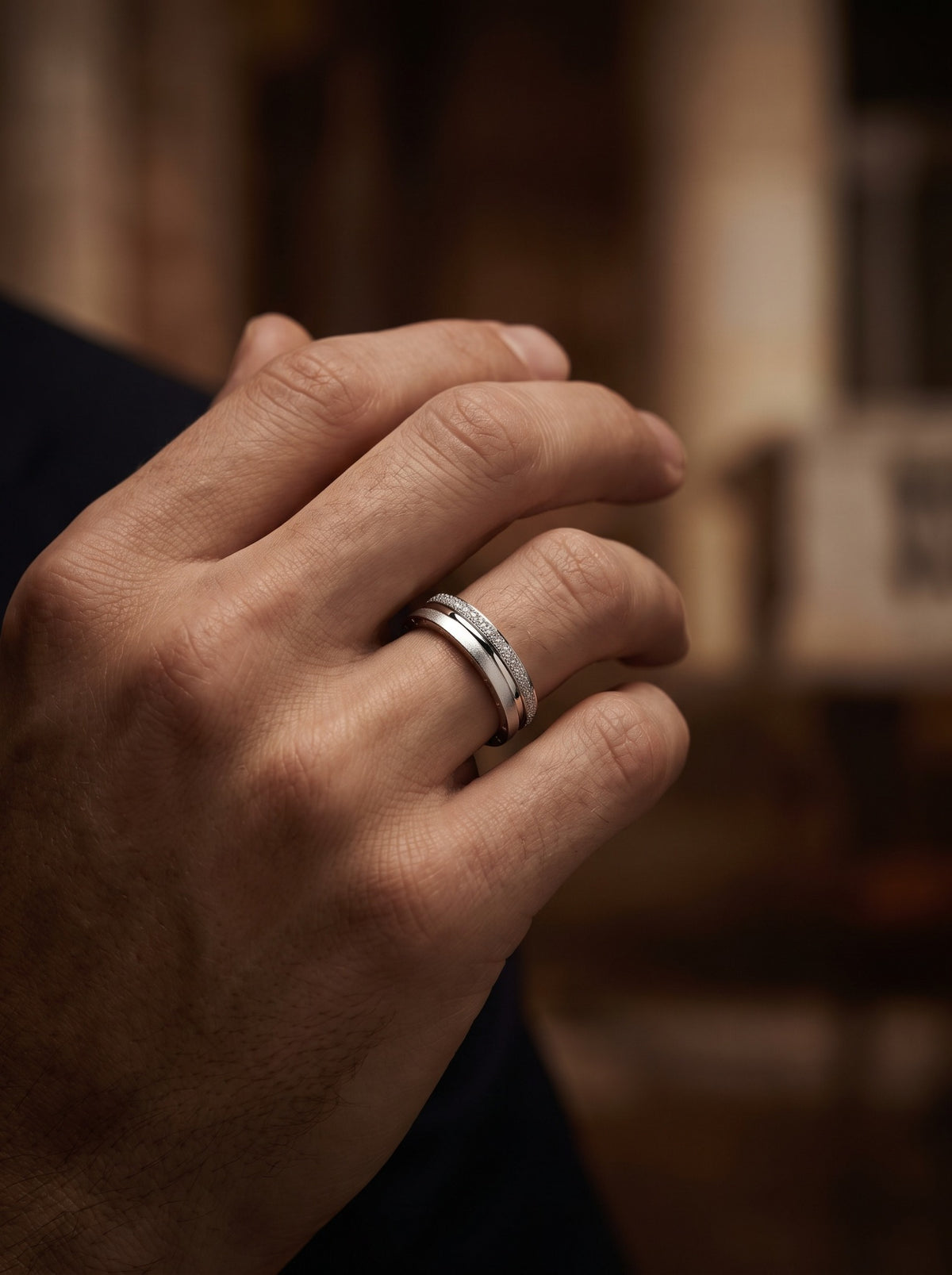 HELIOR Strata PT950 platinum textured wedding band worn on a man's hand in warm light; fit varies by ring size