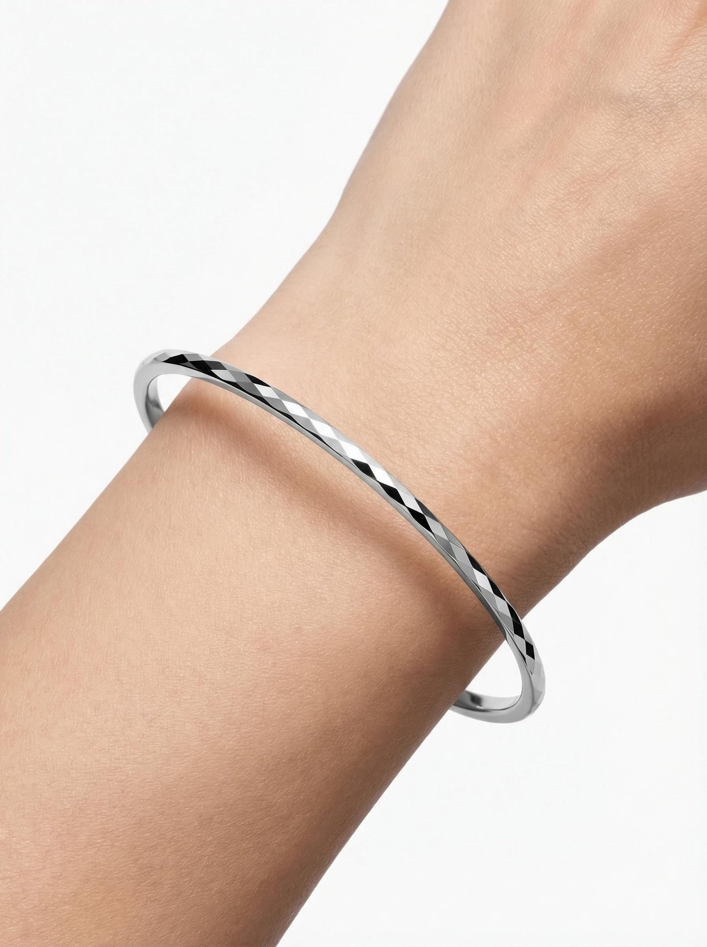Close wrist view of geometric faceted platinum bangle
