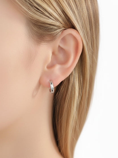 Close ear view of PT950 platinum textured huggie earrings