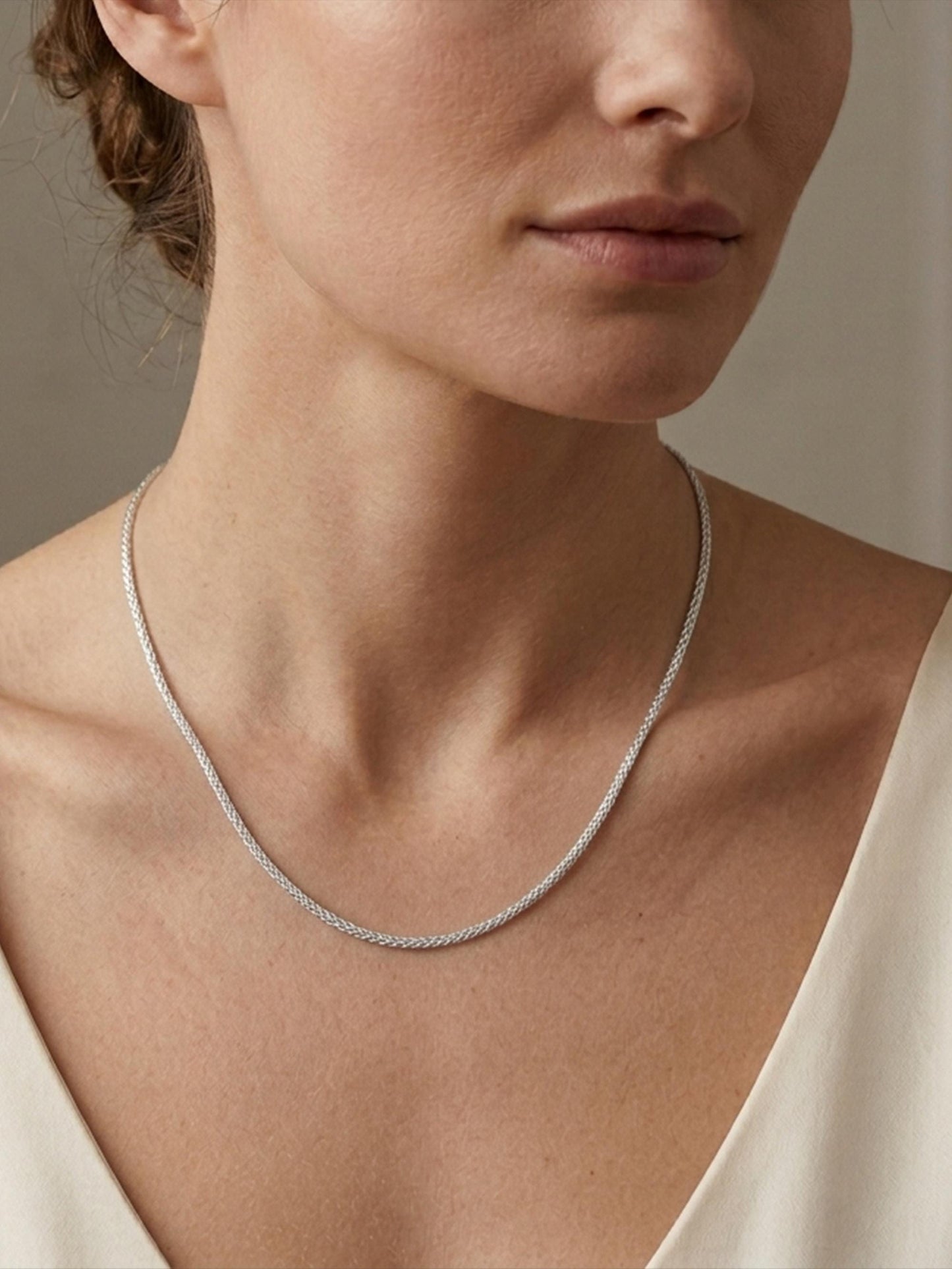 Woman wearing heavyweight platinum foxtail chain with cream neckline