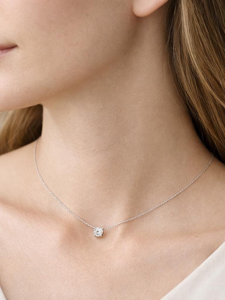 Woman wearing platinum lab-grown diamond solitaire with cream neckline