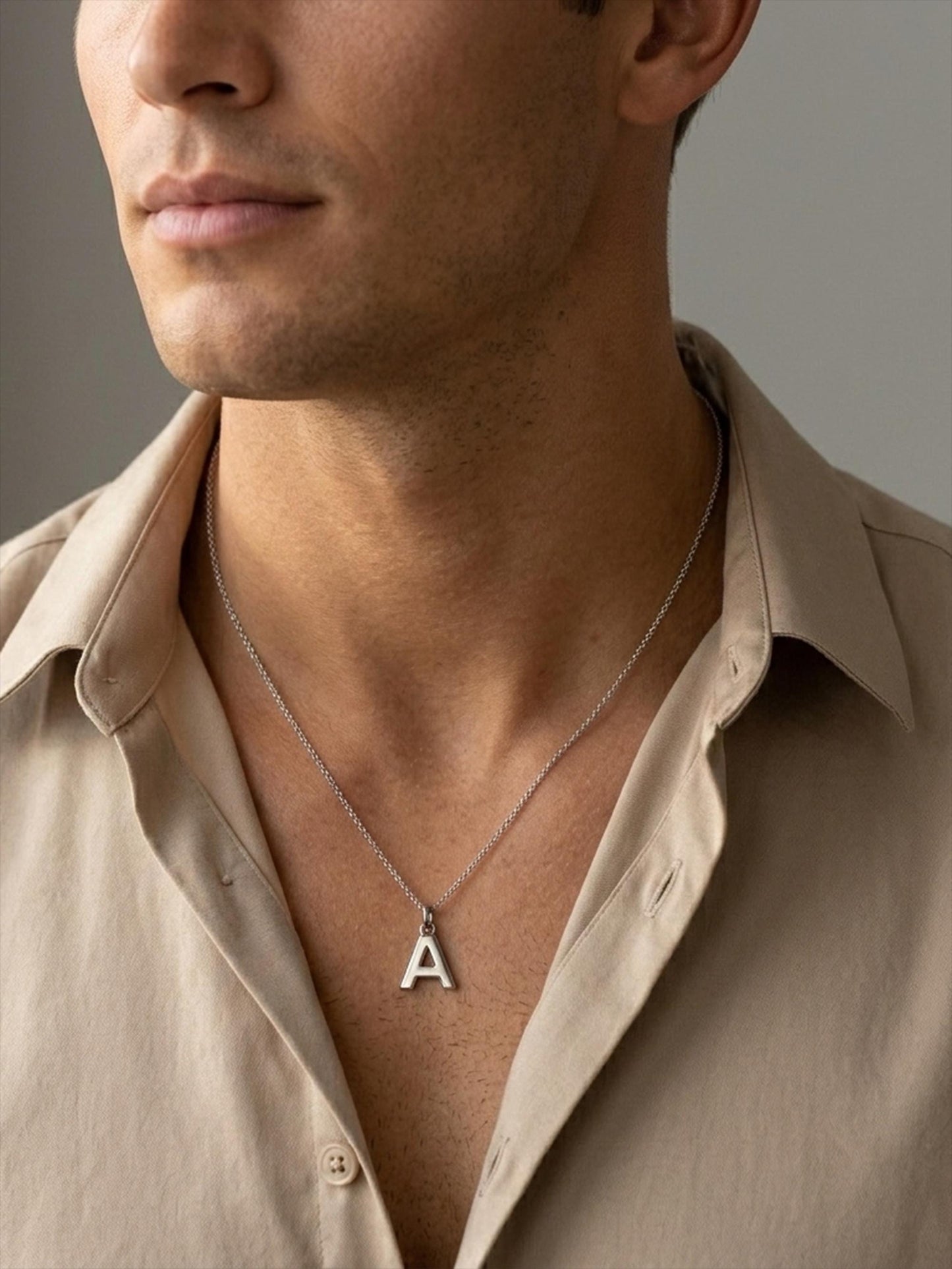 Man wearing platinum letter A initial pendant with beige shirt
