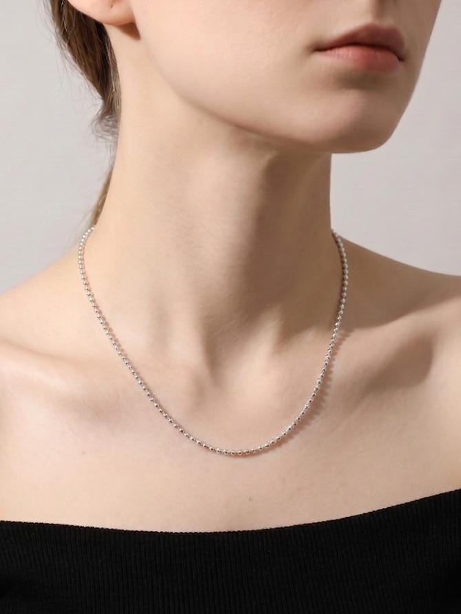 Woman wearing 1.3mm platinum ball-link necklace with black neckline
