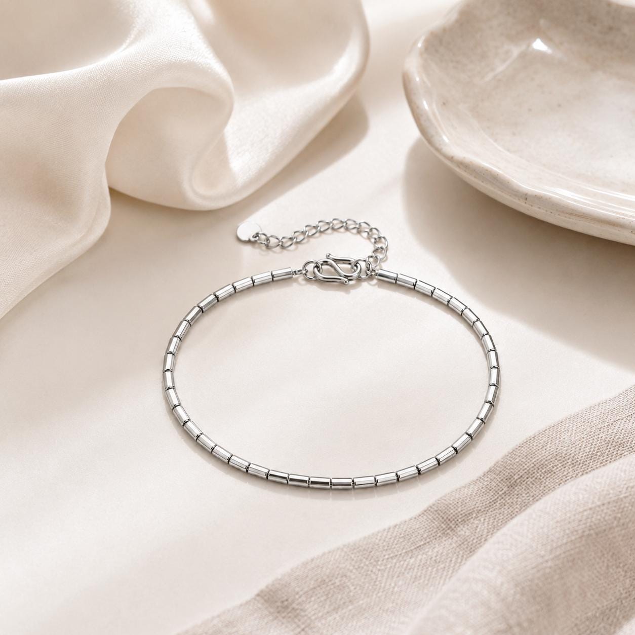 Platinum barrel-link bracelet styled on neutral surface