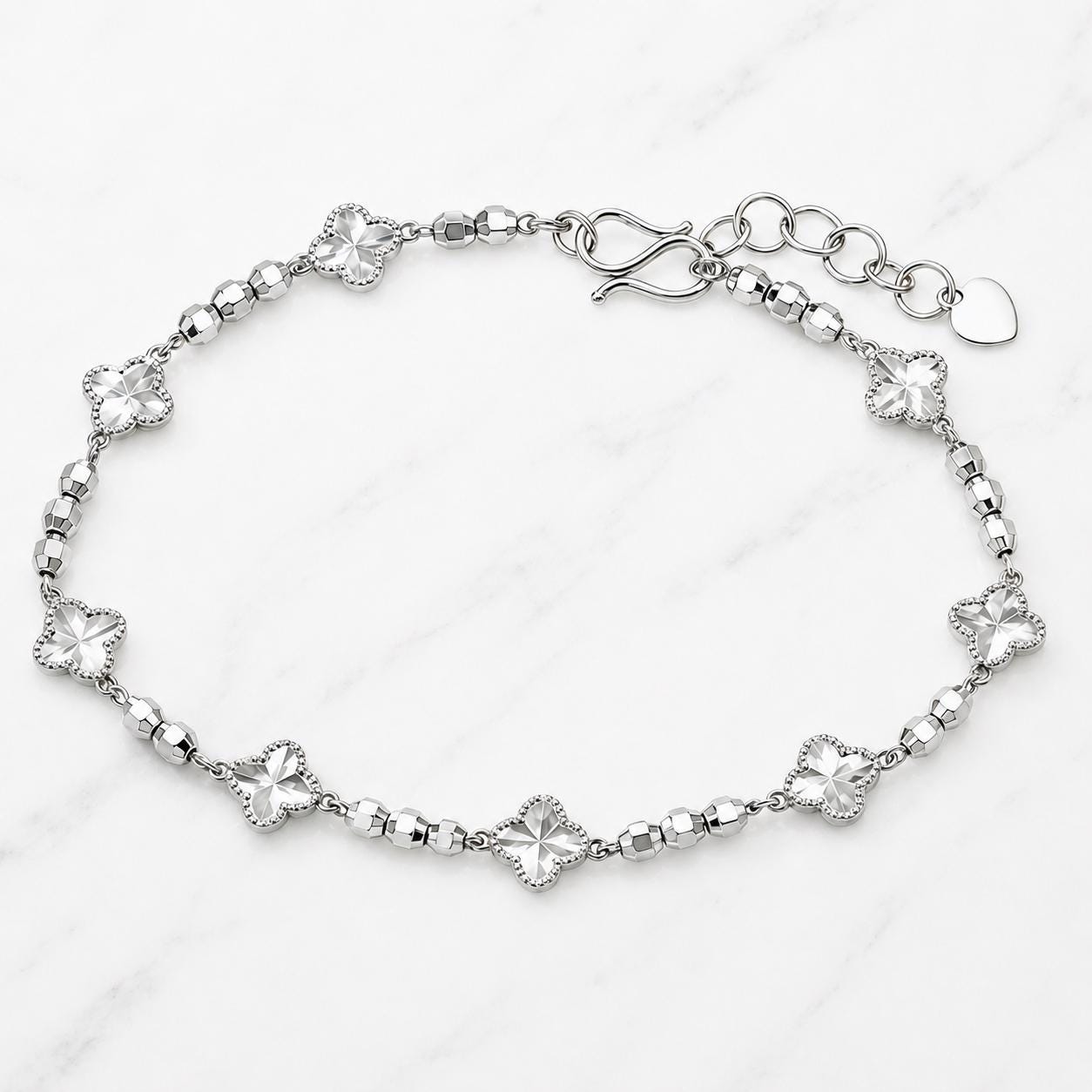 Platinum clover and bead bracelet on marble surface