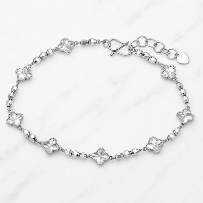 Platinum clover and bead bracelet on marble surface