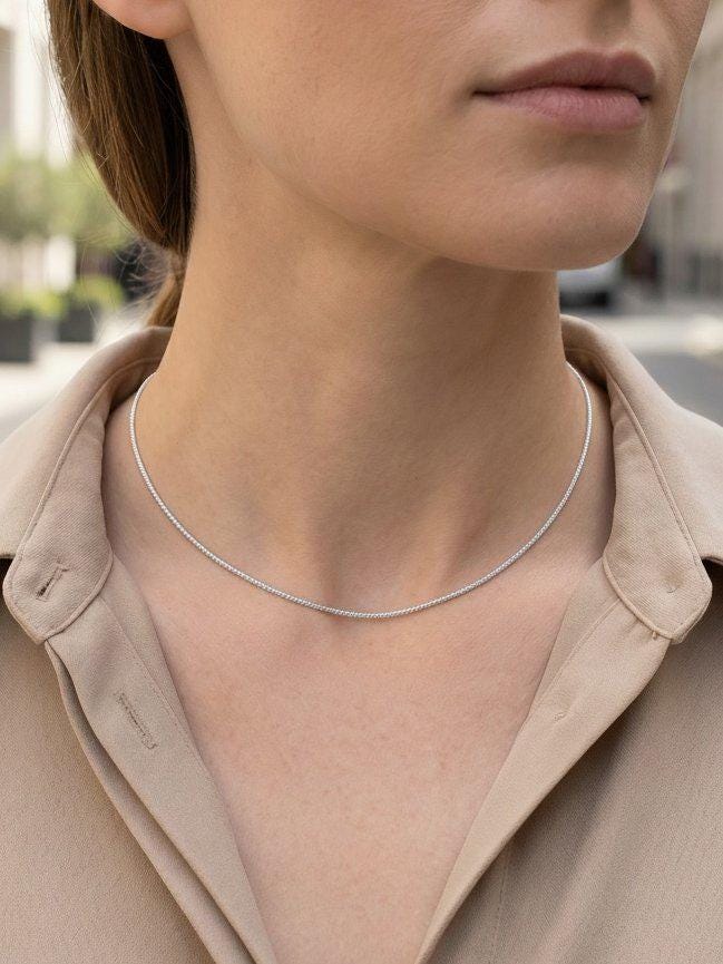 Woman wearing fine 1.2mm platinum wheat chain with beige shirt