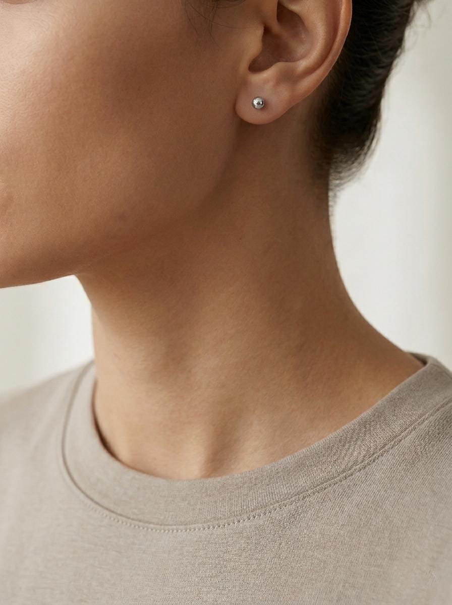 Model wearing PT950 faceted ball stud earrings in profile