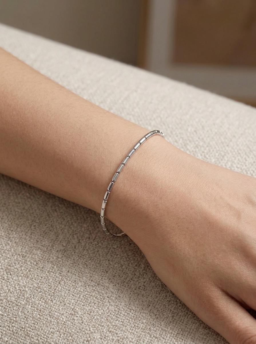Woman wearing slim platinum barrel-link bracelet