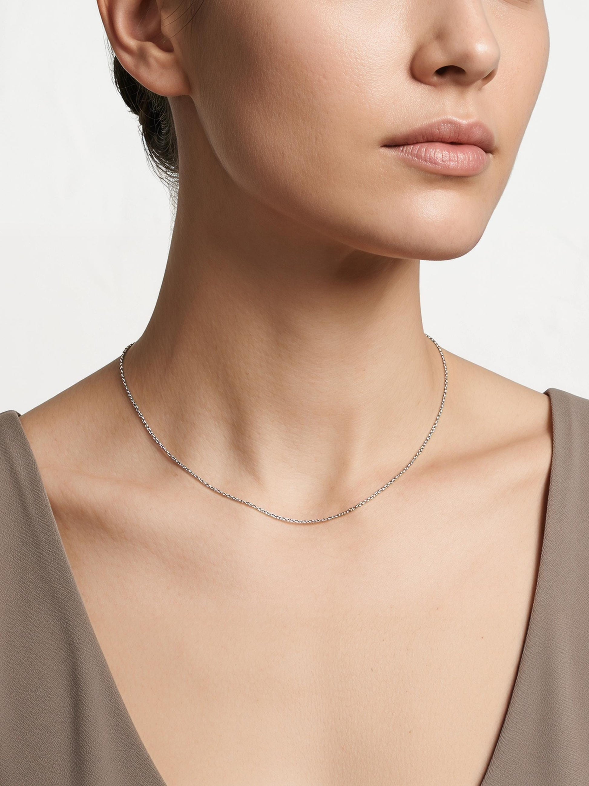 Woman wearing fine platinum cable chain with taupe neckline