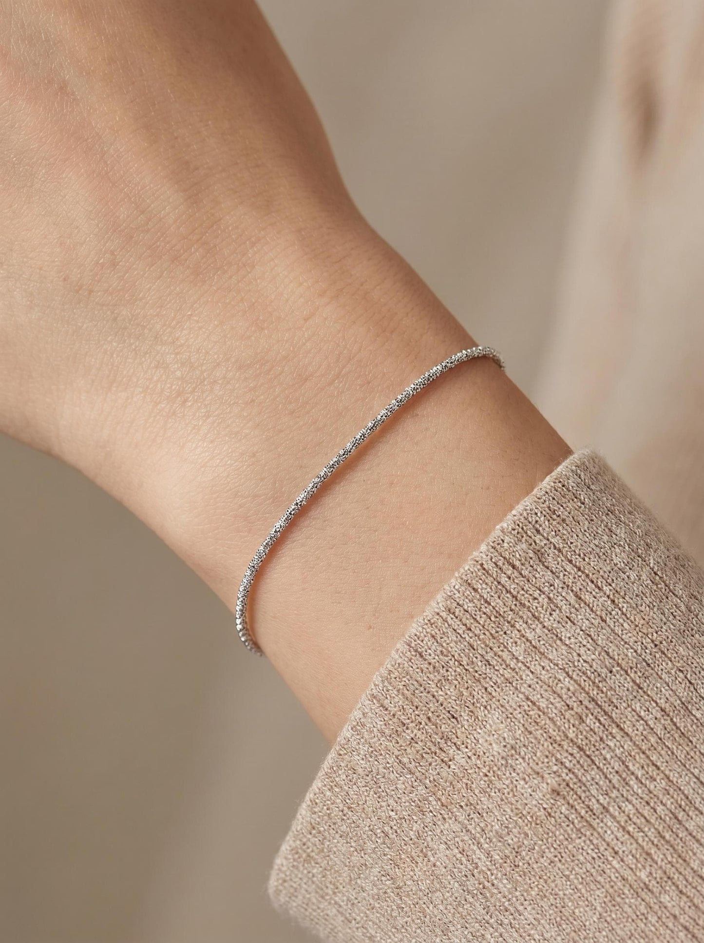 Woman wearing 1.5mm faceted platinum chain bracelet