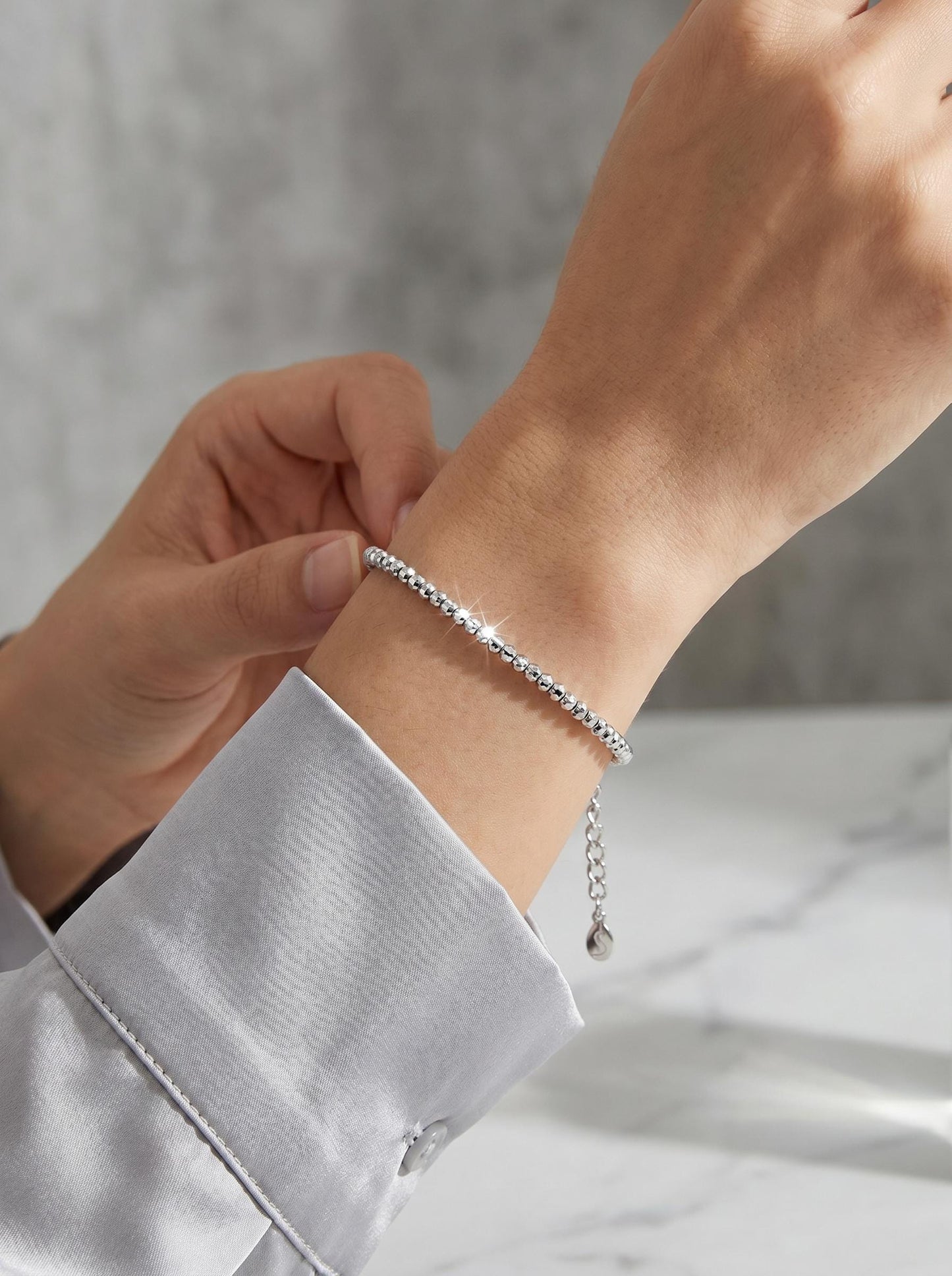 Woman wearing faceted platinum bead bracelet