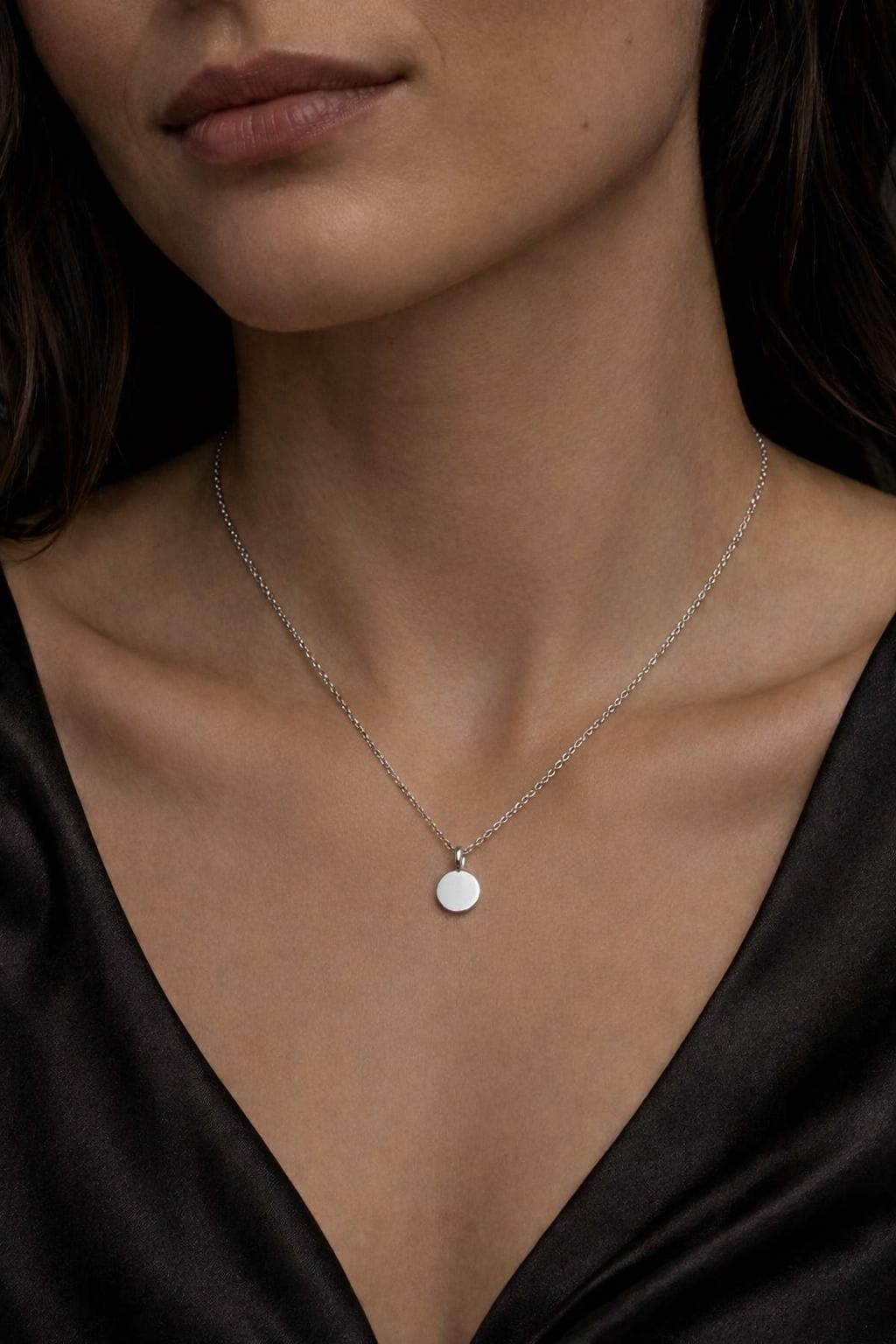 Woman wearing polished platinum disc necklace with black satin neckline
