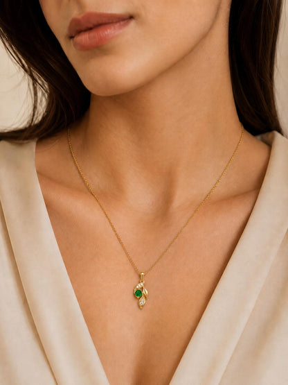 Woman wearing 18K gold emerald leaf pendant with cream V-neck