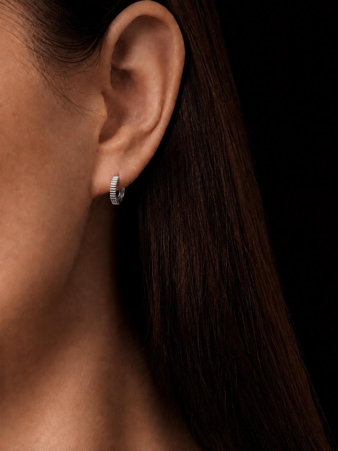 Woman wearing solid PT950 ridged huggie hoop earrings