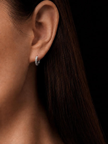 Woman wearing solid PT950 ridged huggie hoop earrings