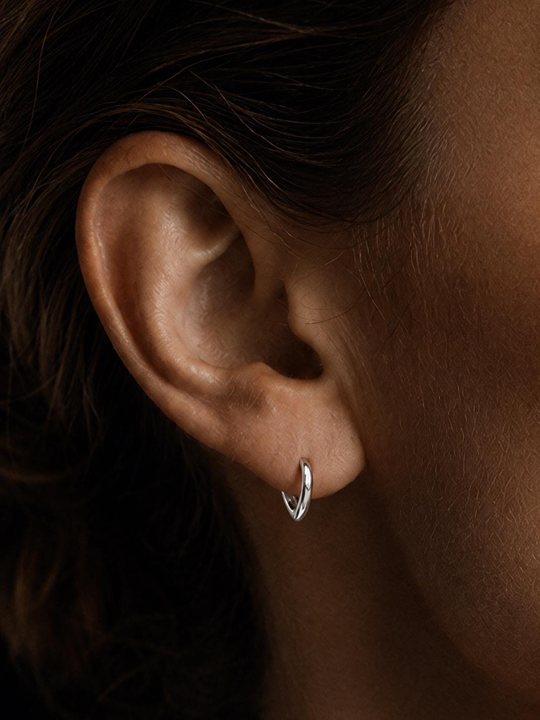 Model wearing solid PT950 teardrop huggie hoop earrings