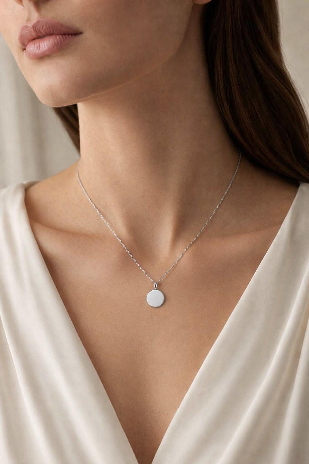 Woman wearing personalised PT950 disc pendant with cream satin neckline