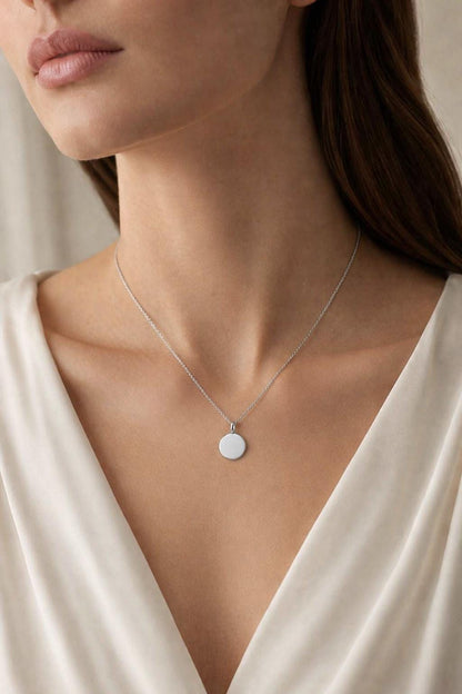 Woman wearing personalised PT950 disc pendant with cream satin neckline