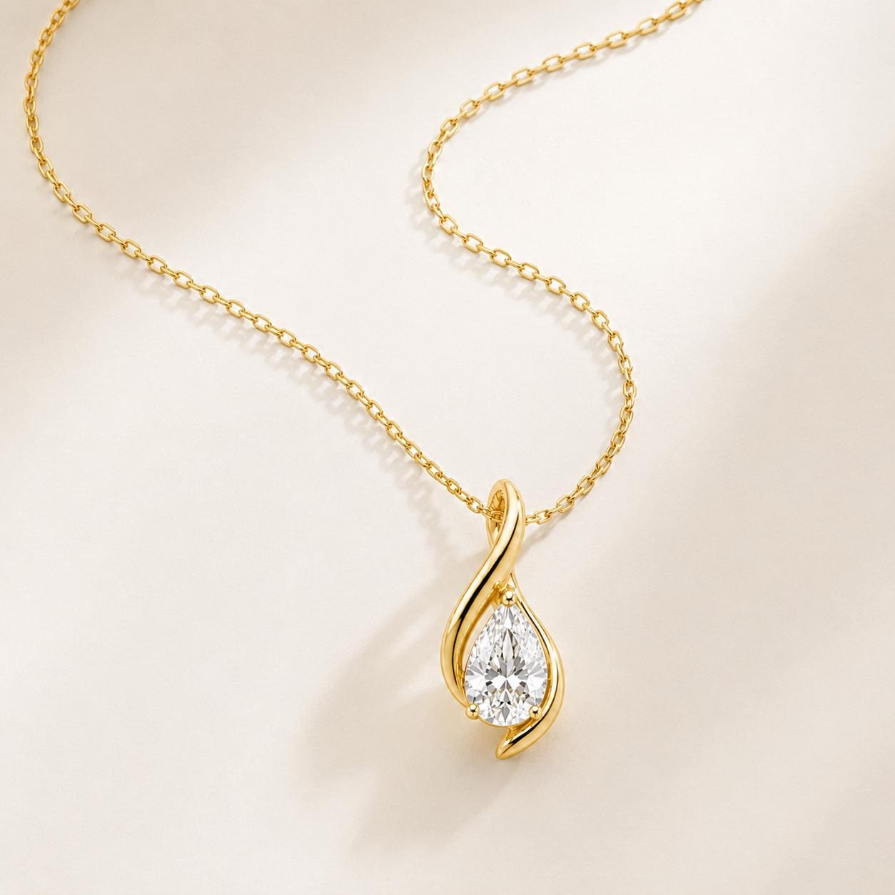 Yellow gold pear diamond twist pendant arranged on ivory satin