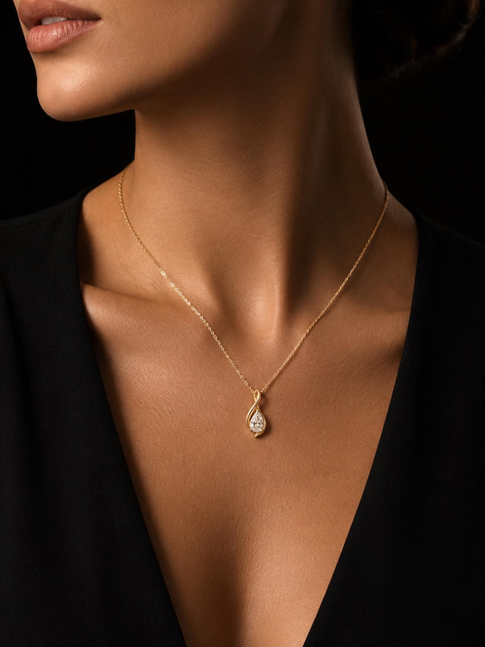 Close portrait of woman wearing pear diamond twist pendant on black