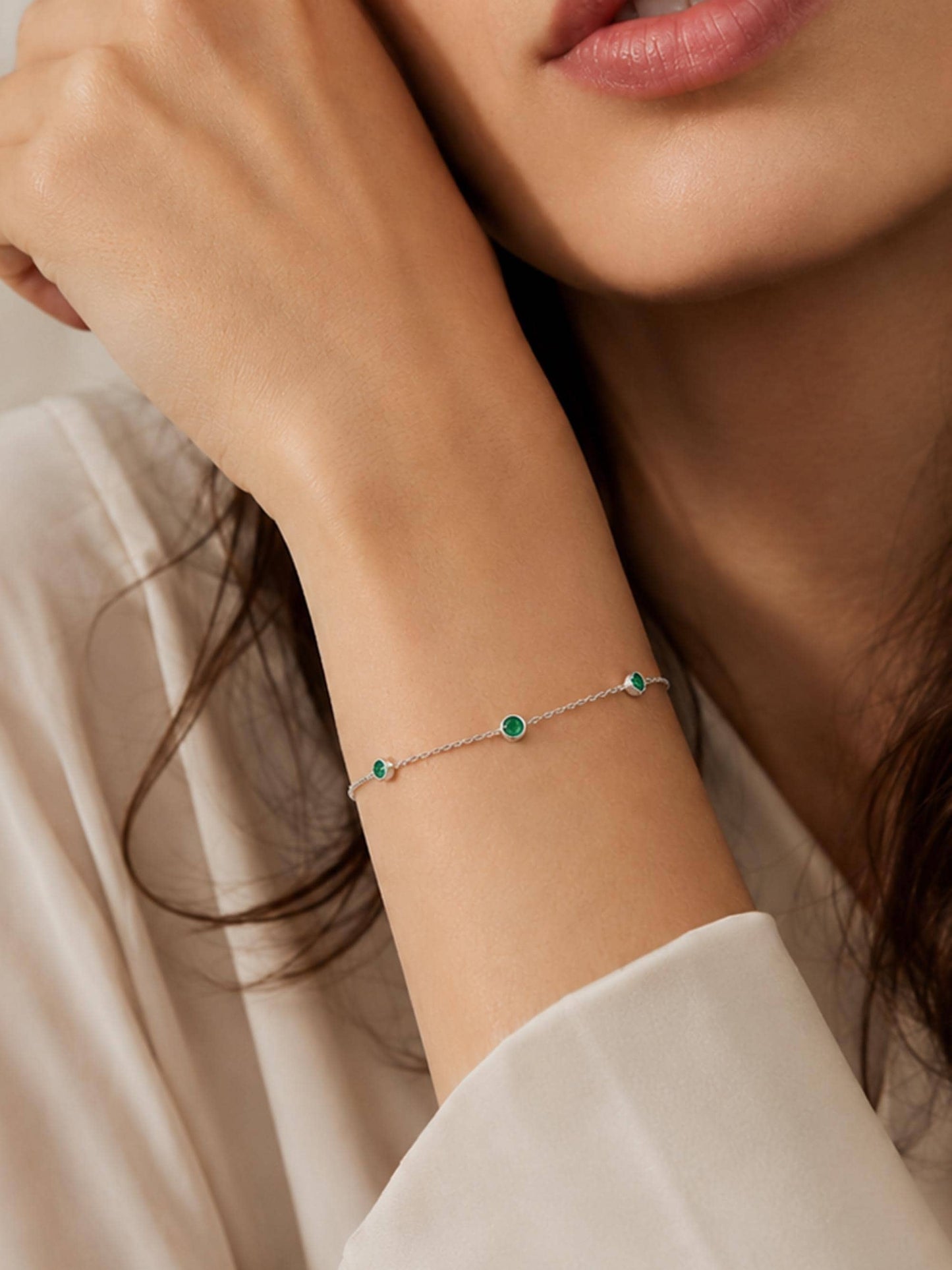 Woman wearing three-stone emerald platinum bracelet