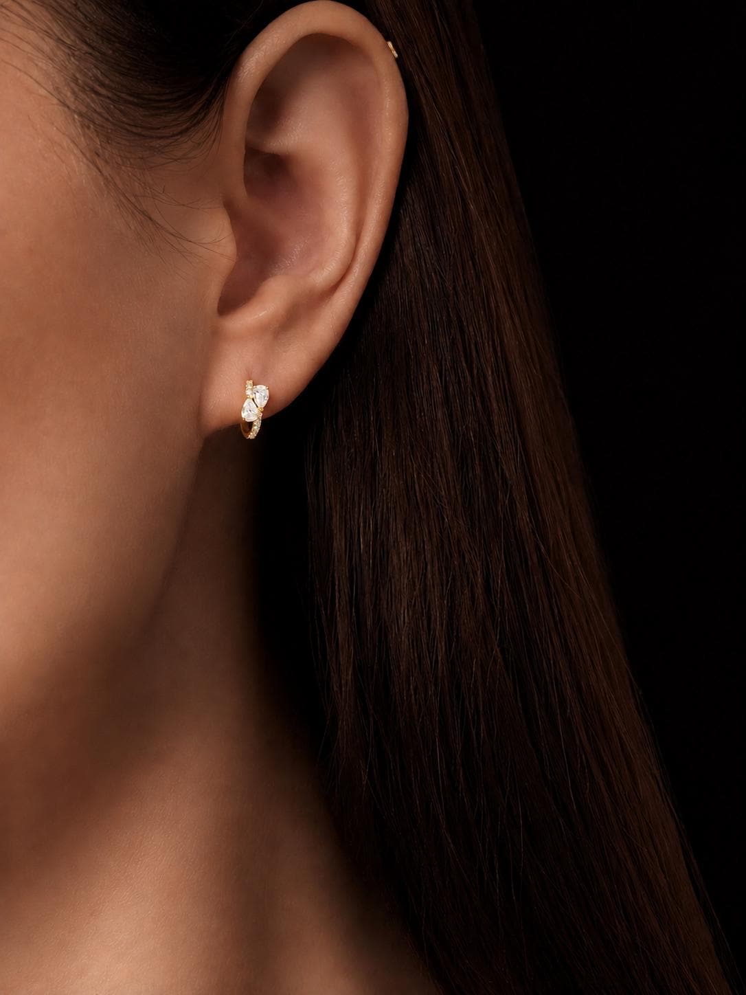 Model wearing 18K gold pear cluster lab diamond huggie earrings