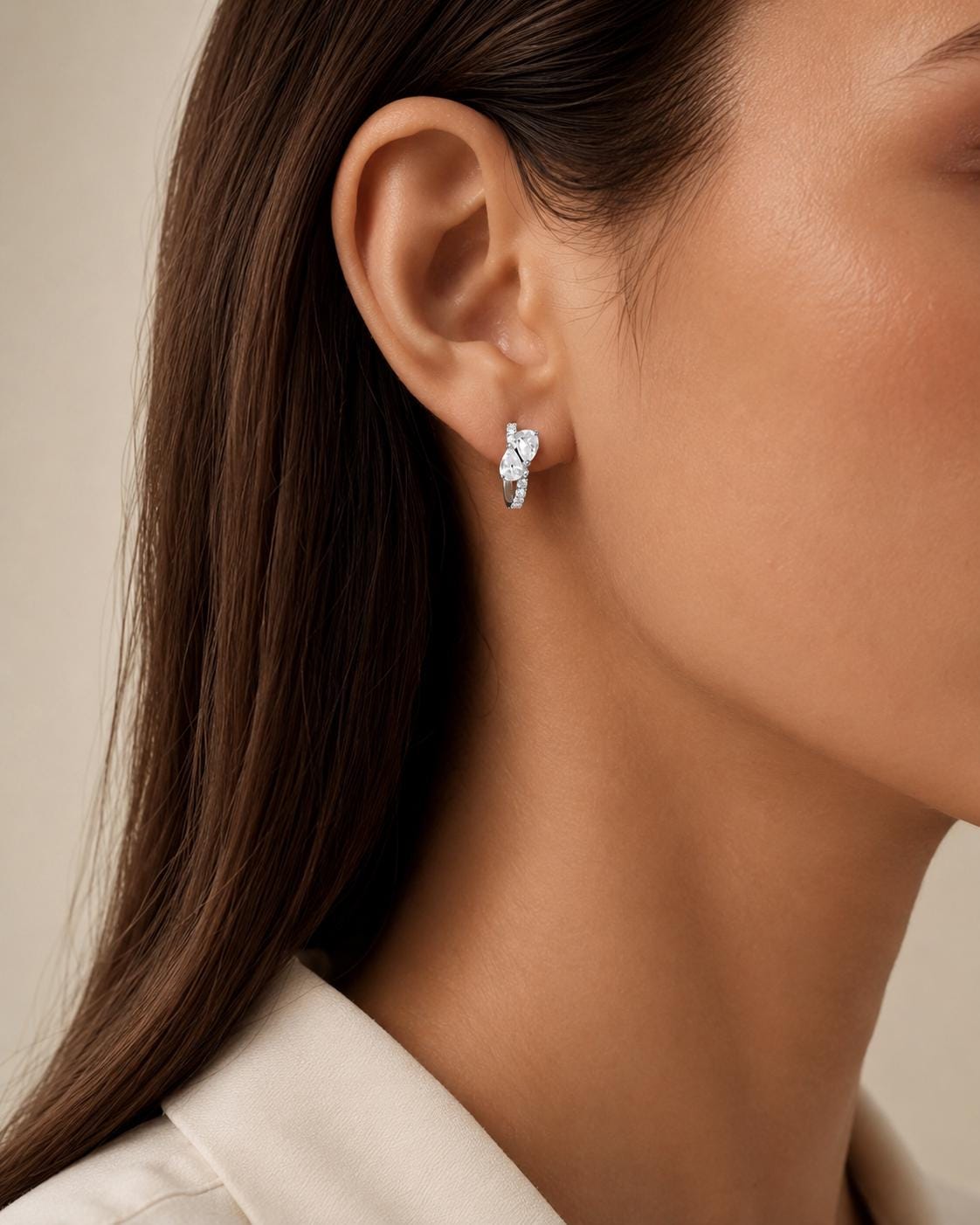 Model wearing platinum pear cluster diamond huggies in profile
