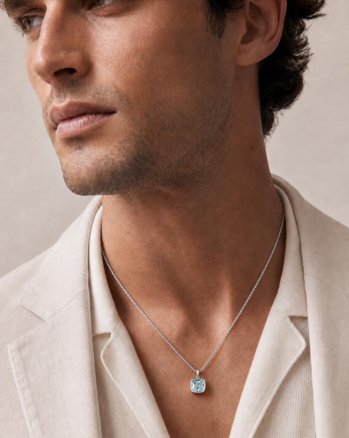 Man wearing PT950 platinum blue topaz necklace with cream blazer